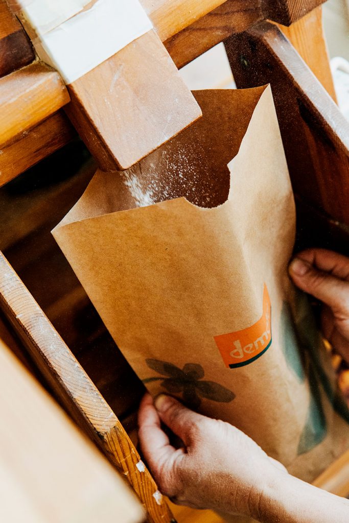 Eine Papiertasche wird mit Mehl befüllt.