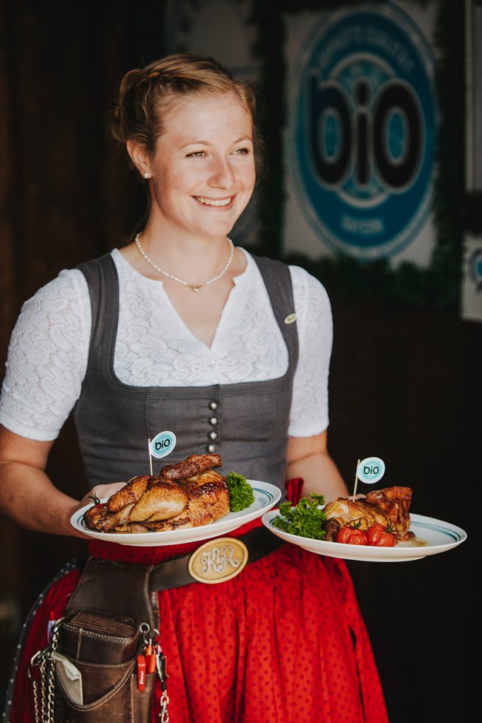 Eine Wiesnbedienung trägt zwei Teller.